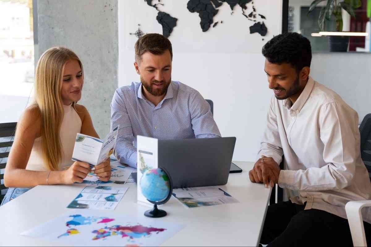 Three individuals seated at a table, collaborating over a laptop in a casual setting.